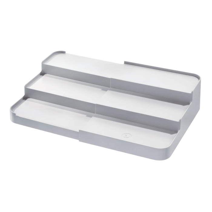 The iDesign Spice Rack Side Caddy, eco-friendly and made from recycled plastic, features a white and gray tiered design with three expandable levels, perfect for organizing jars on countertops or inside cabinets.