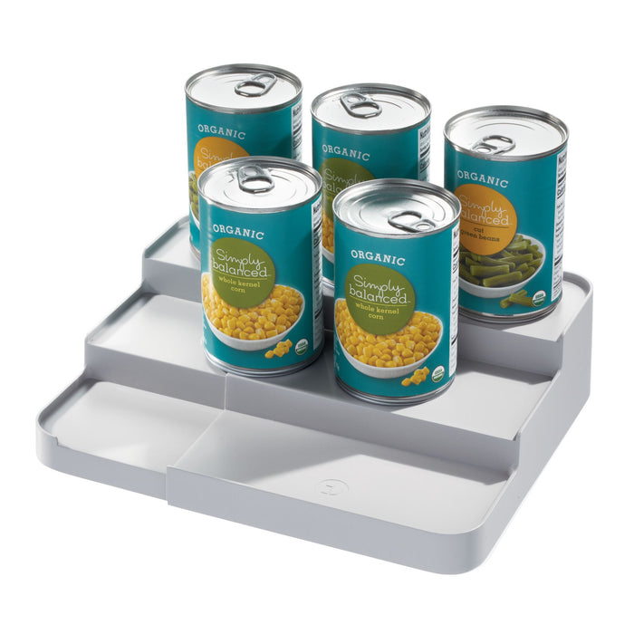 Five cans of organic vegetables, such as corn and green beans, are neatly displayed on iDesigns Spice Rack Side Caddy. This gray organizer, made from recycled plastic with a three-level design, offers easy access and eco-friendly kitchen storage.