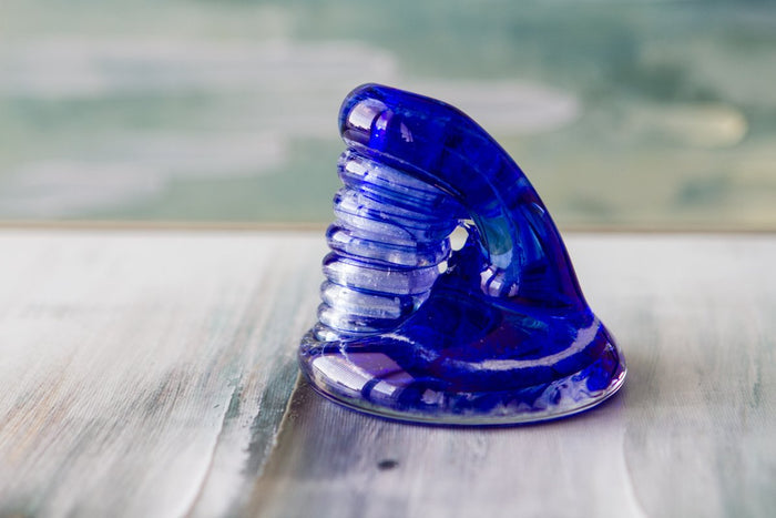 Blue glass Spiral Bud Vase with cremains on a light wooden surface