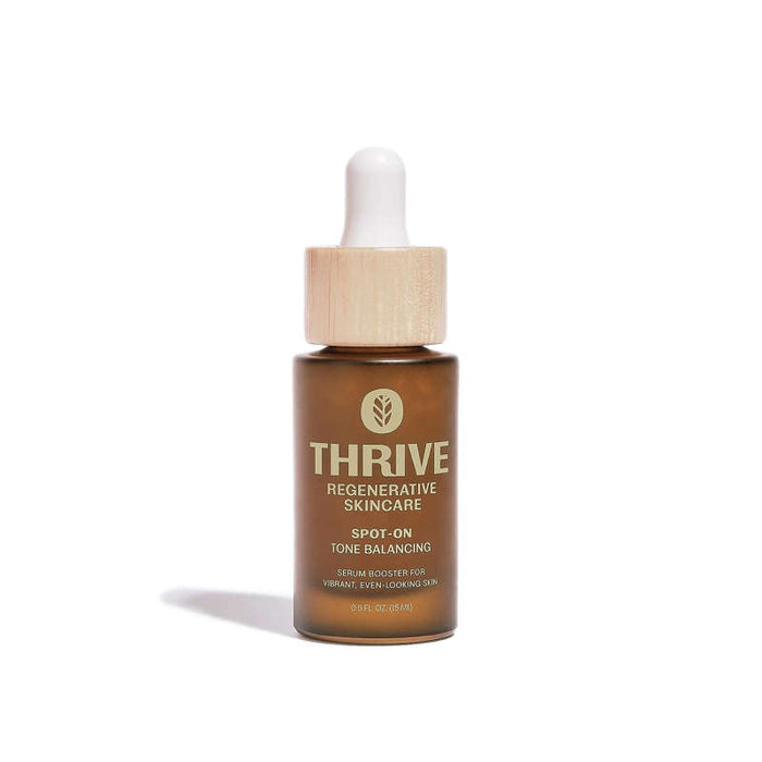 A small brown bottle of Thrive Natural Cares Spot-On Tone Balancing Serum, crafted to even skin tone and reduce dark spots, featuring a white dropper cap. It stands on a white surface with a subtle shadow.
