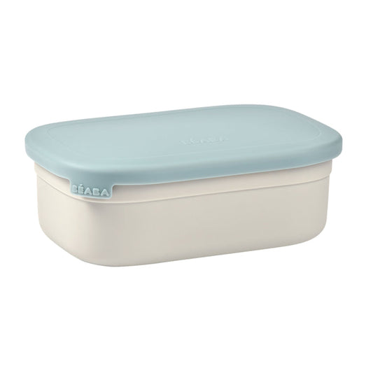 A BEABA Stainless Steel Bento Lunch Box featuring a rectangular design with light blue lid and white eco-friendly body. The fitted lid has silicone dividers, and the brand name is subtly embossed on both the lid and side.