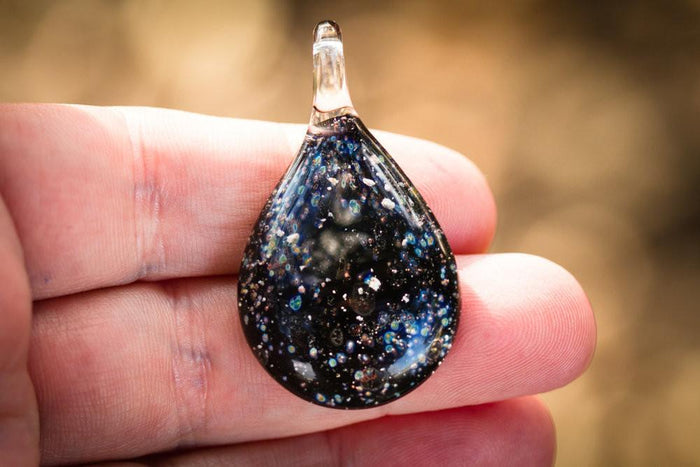 Teardrop Starry Night cremation ash pendant in lamp-worked glass with blue black background and star specks