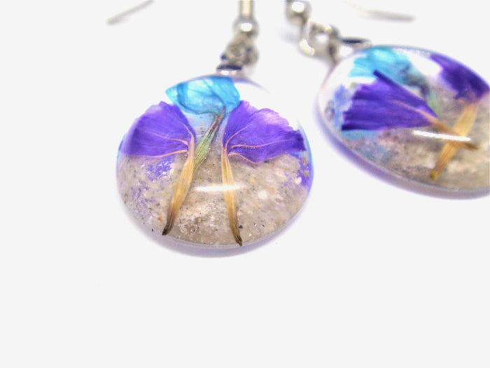 Round resin earrings featuring purple statice flowers encased in clear resin with silver ear wires
