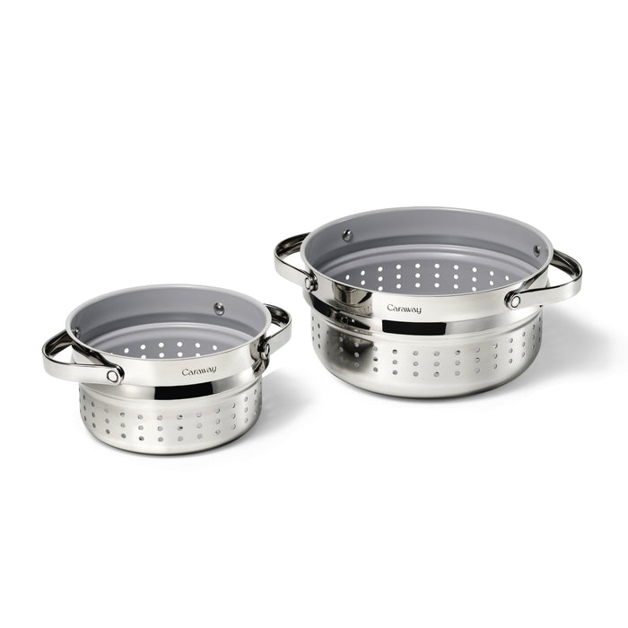 The Steamer Duo, by Caraway, features two metallic colanders with a polished finish and perforated holes, medium and large in size. They are displayed side by side on a white background with the brand name on a dark label.