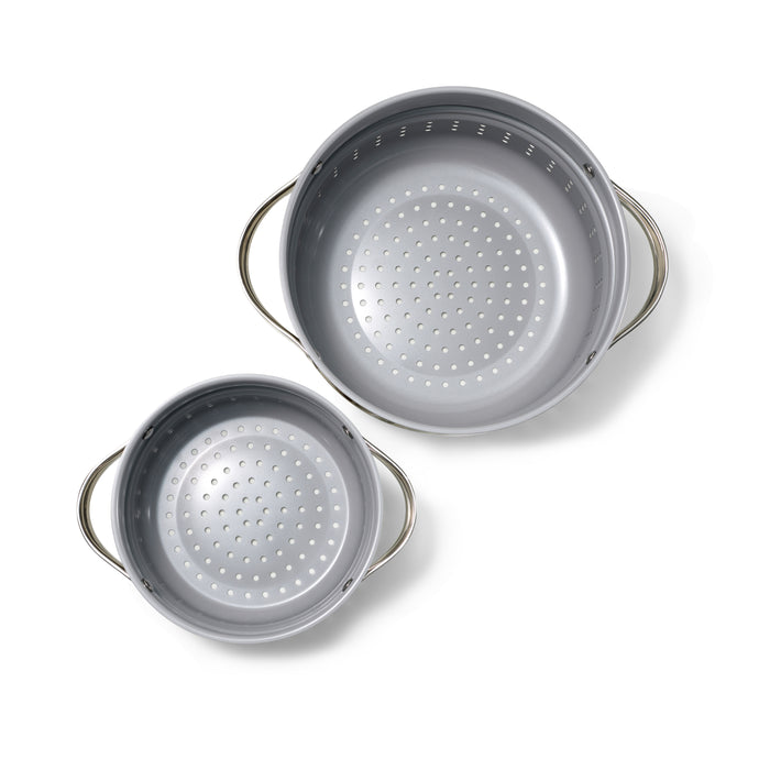 The Caraway Steamer Duo, with its two metal colanders featuring perforated bottoms, is displayed on a white background. Different sizes and matching side handles ensure easy lifting, while the symmetrical patterns enhance the non-stick steamers functionality.