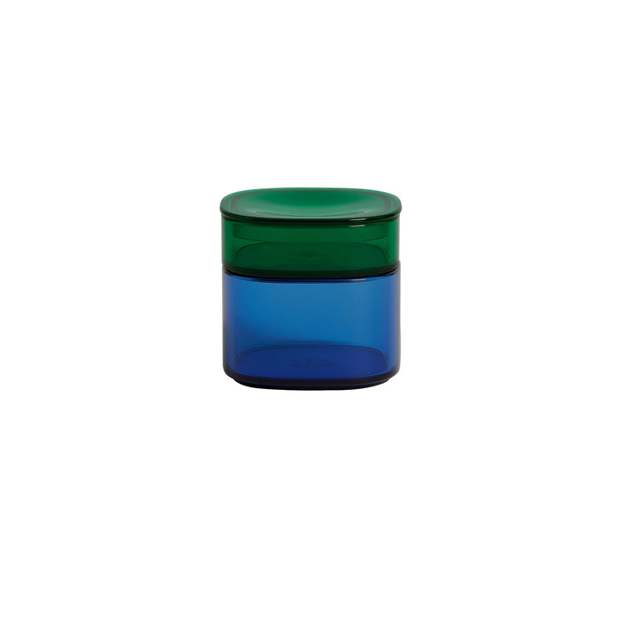 Against a white backdrop, the Storage Gems by Open Spaces—small cylindrical acrylic containers with a blue base and green lid—gleam in an organized space.