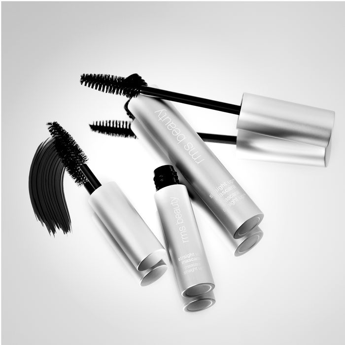 The RMS Straight Up™ Volumizing Peptide Mascara features four silver tubes with wands on a light background, each bristle-topped with black. One wand shows a stroke of mascara beside it. This clean collection boasts white text and promises volume and nourishment from peptides.