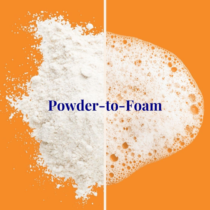 A split image shows powder on the left and foam on the right against an orange background, highlighting The Powder Shampoos Strengthening & Soothing Powder Shampoo. The text Powder-to-Foam is centered in blue, infused with hints of Grapefruit Essential Oil for a refreshing twist.