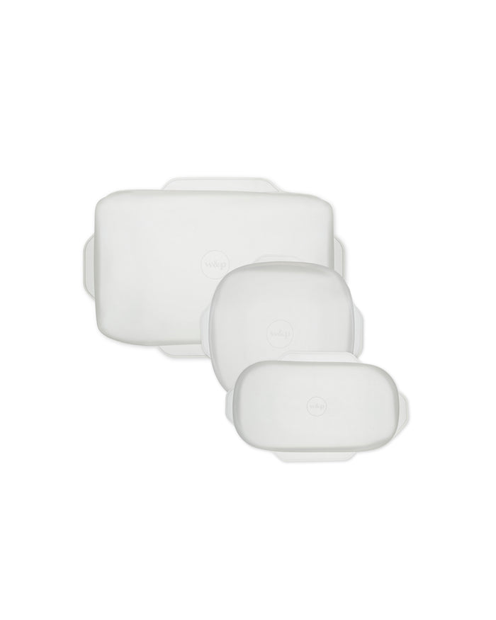 On a pristine white backdrop, three versatile rectangular Stretch Baking Lids by W&P, in varying sizes with transparent designs and rounded edges, offer an eco-friendly alternative to single-use items as part of innovative food storage solutions.