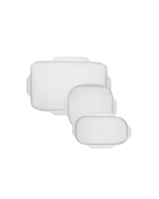 On a pristine white backdrop, three versatile rectangular Stretch Baking Lids by W&P, in varying sizes with transparent designs and rounded edges, offer an eco-friendly alternative to single-use items as part of innovative food storage solutions.