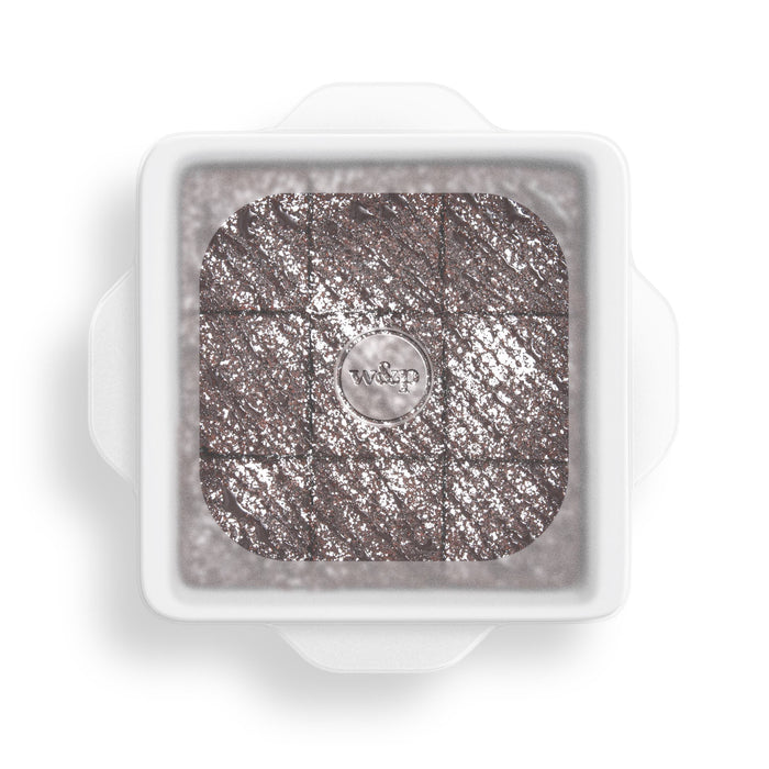 The W&P Stretch Baking Lids feature a chic, square tray with a clear lid showcasing nine glittery, textured metallic cubes. Adorned with a small circular emblem at the center of the lid, it offers an elegant and reusable food storage solution.