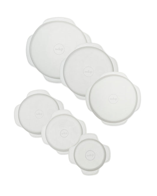 The Stretch Lids by W&P come as a set of six reusable, round, white silicone lids for versatile food storage. They feature small tabs around the edges and an embossed w&p logo in the center, with varying sizes arranged in two columns.