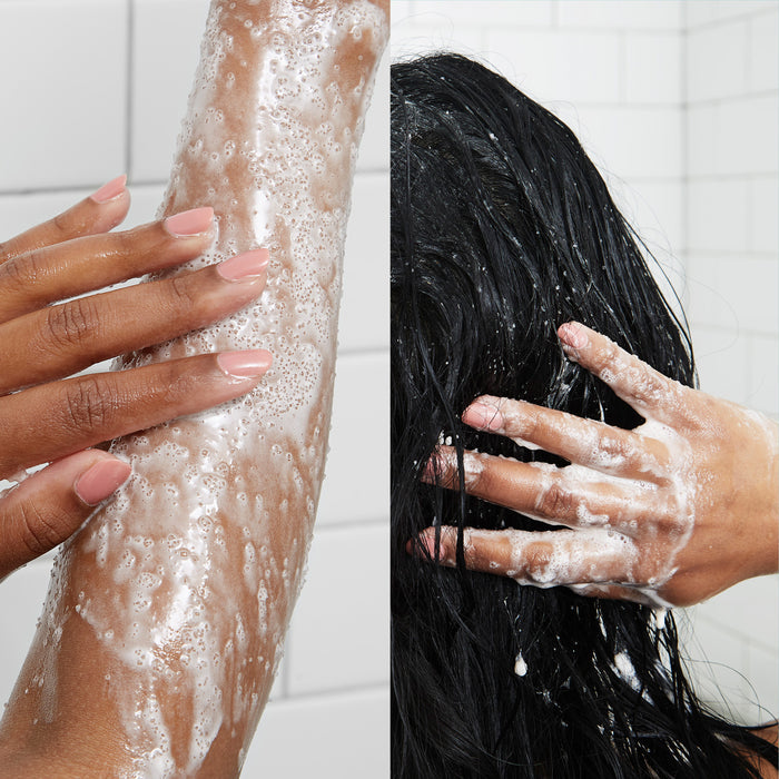 Split image: Left displays a hand applying VOESH New Yorks Sugar Scrub + Bubble Wash on an arm in a tiled bathroom. Right shows someone washing long, wet hair, covered in white foam from the same product, with fingers spread.