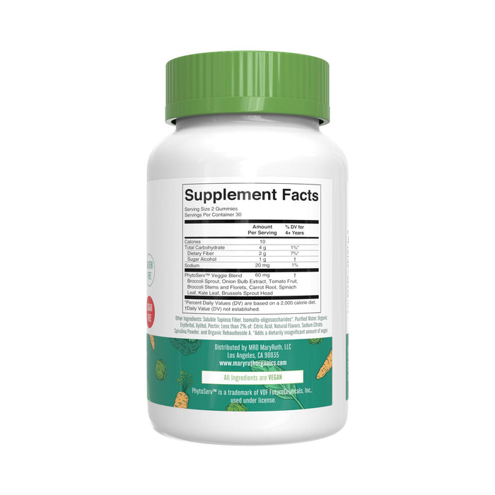 A white Super Greens Gummies bottle from MaryRuth’s with a green cap displays a Supplement Facts label listing nutrients like Quercetin. Green leaves and herbs decorate the background, and brand details below the label highlight vegan gummies.
