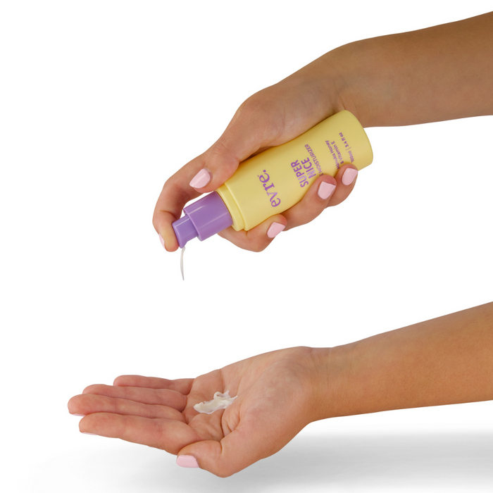 Two hands are shown. One holds a yellow bottle with a purple pump, dispensing white lotion enriched with Jojoba Oil into the open palm of the other hand. The bottle features purple text and is labeled as Super Nice Mānuka Honey & Vitamin E Face Moisturizer by evre.