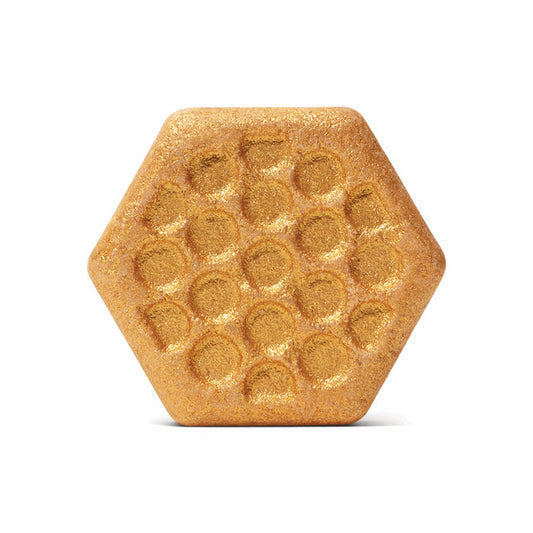 The Sweet Honey Almond Froth Bomb by Pacha Soap Co. is a gold, hexagon-shaped bath bomb with a honeycomb pattern and glittery surface—ideal for fans of natural, cruelty-free bath products.