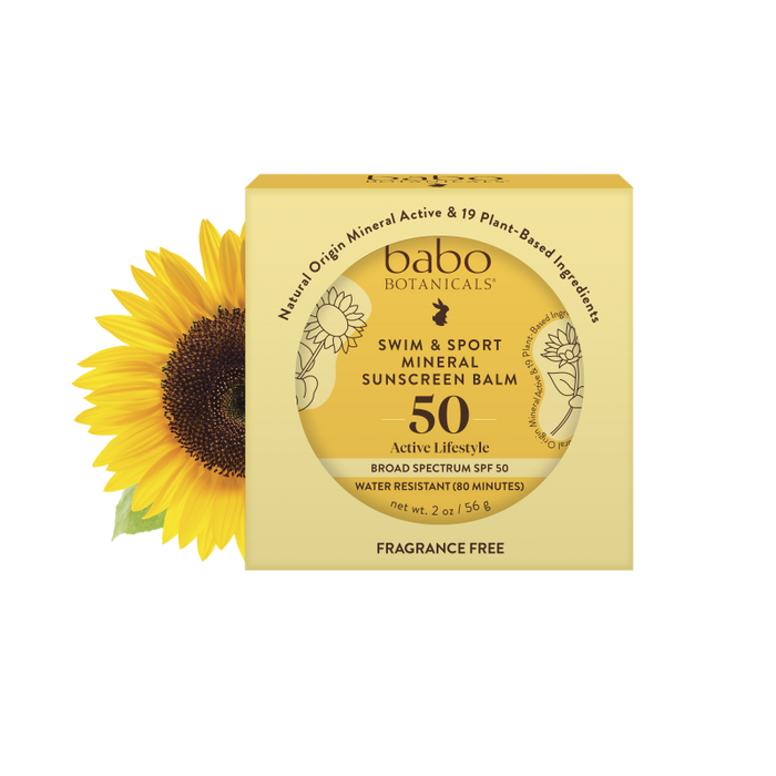 The yellow, travel-friendly box of Babo Botanicals Swim & Sport Mineral Balm - SPF 50 showcases a sunflower design. It provides broad-spectrum protection, is water-resistant for 80 minutes, fragrance-free, and comes in eco-friendly packaging.