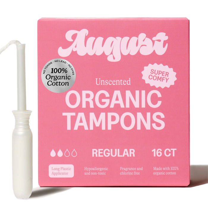 A pink August Regular Tampon box displays Super Comfy and 100% Organic Cotton badges. Next to it is a white hypoallergenic tampon with a BPA-free applicator. Each box contains 16 regular tampons.