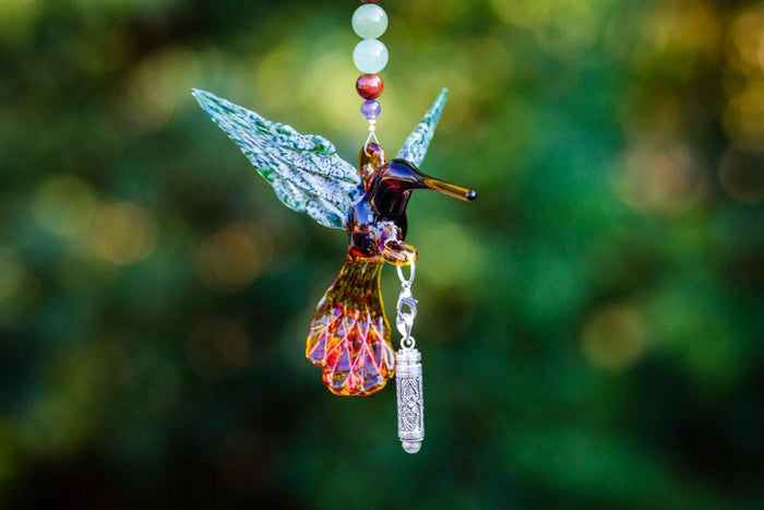 Handmade glass hummingbird pendant with green iridescent wings amber body crystal butterfly topper beaded strand and detachable keepsake urn for ashes.
