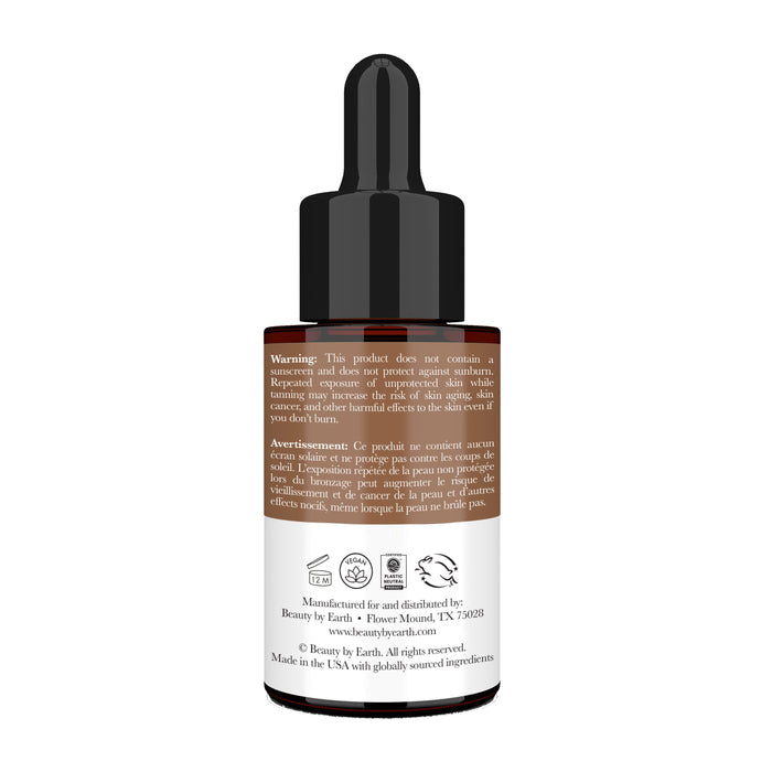 A brown glass bottle with a black cap holds Beauty by Earth Tanning Drops. The label has English and French warnings, manufacturing details, and a website link. Infused with organic ingredients, it delivers a natural-looking tan while nourishing your skin.