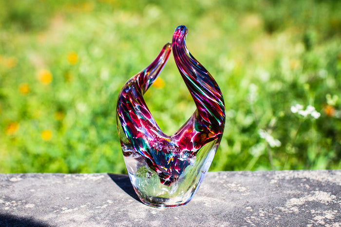 Taurus inspired glass sculpture with two curved horns and a multicolored swirl body infused with cremation ashes