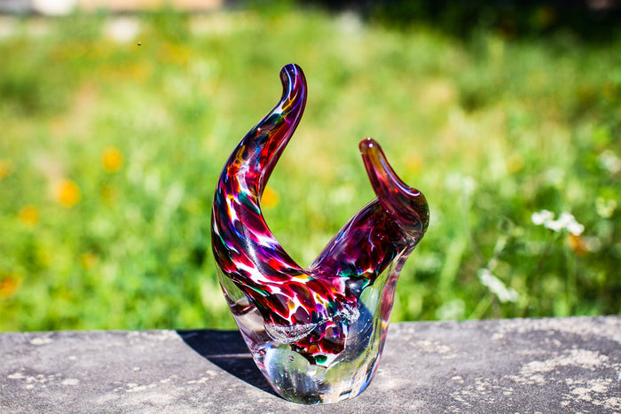 Colorful Taurus glass sculpture with two curved horns rising from a clear base, rainbow swirls throughout the glass