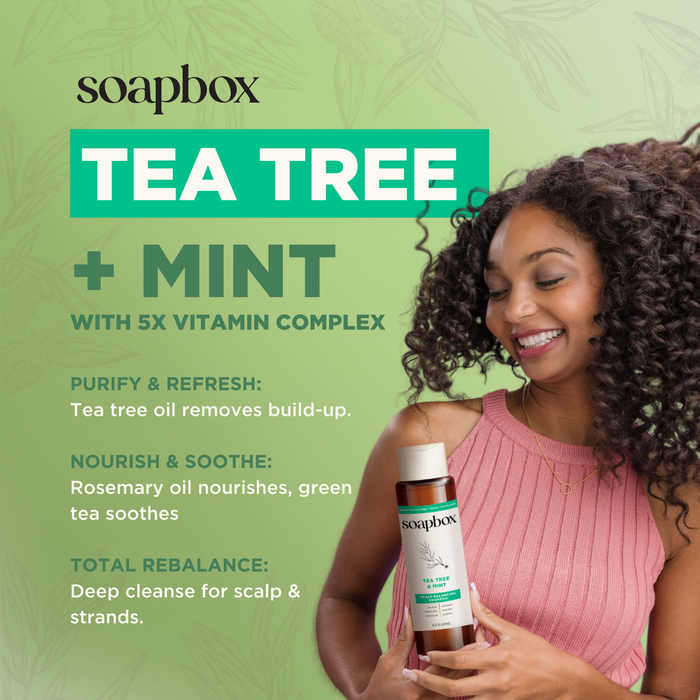 A person with curly hair smiles, holding Soapbox Tea Tree & Mint Scalp Balancing Shampoo. The green background highlights its benefits: purify, nourish, and rebalance scalp and hair with refreshing tea tree oil and a powerful 5x vitamin complex.