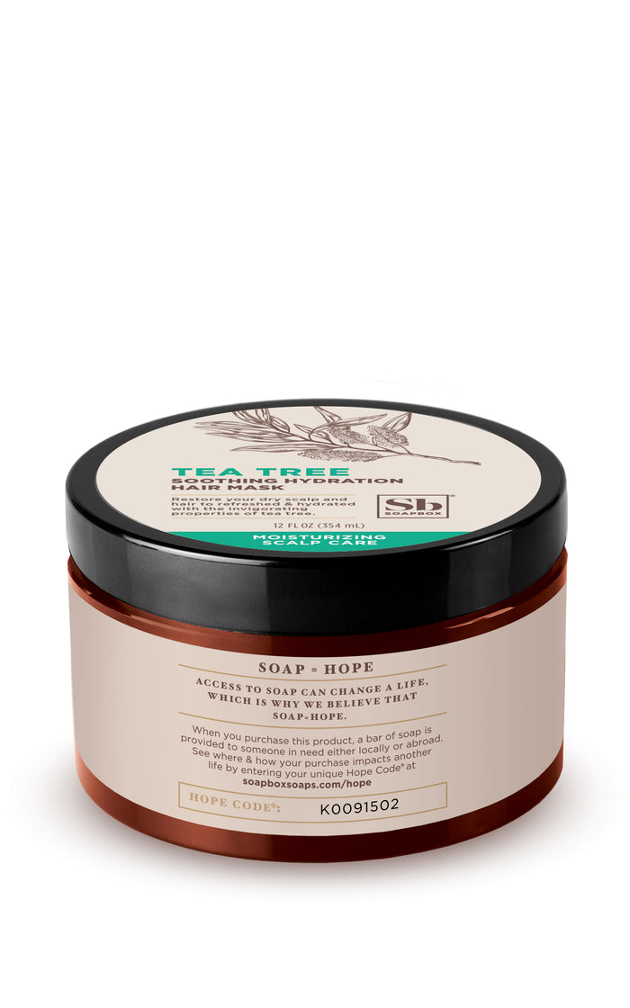 A round, dark amber container with a black lid labeled Tea Tree Soothing Hydration Hair Mask features tea tree oil benefits. The front label emphasizes Soapbox, highlighting soap access and life change. A code K00915O2 is prominently displayed at the bottom.
