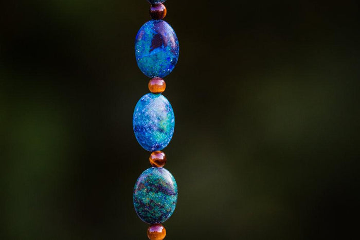 Vertical strand of turquoise blue beads with small orange spacers against a dark background