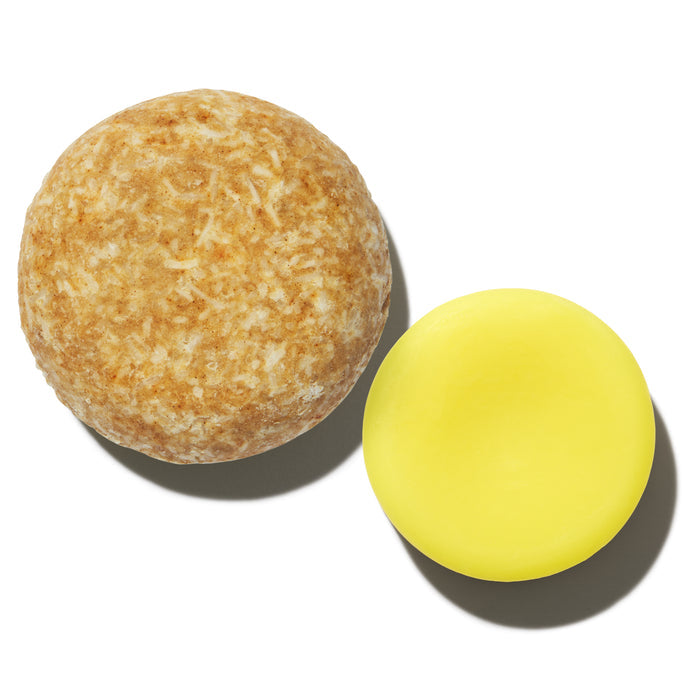 A round, textured beige soap bar rests next to a smooth, vibrant yellow shampoo and conditioner bar on a plain white background. Enjoy frizz-free, silky hair with the eco-friendly The Balancer Travel Set by NOT!CE Hair Co.