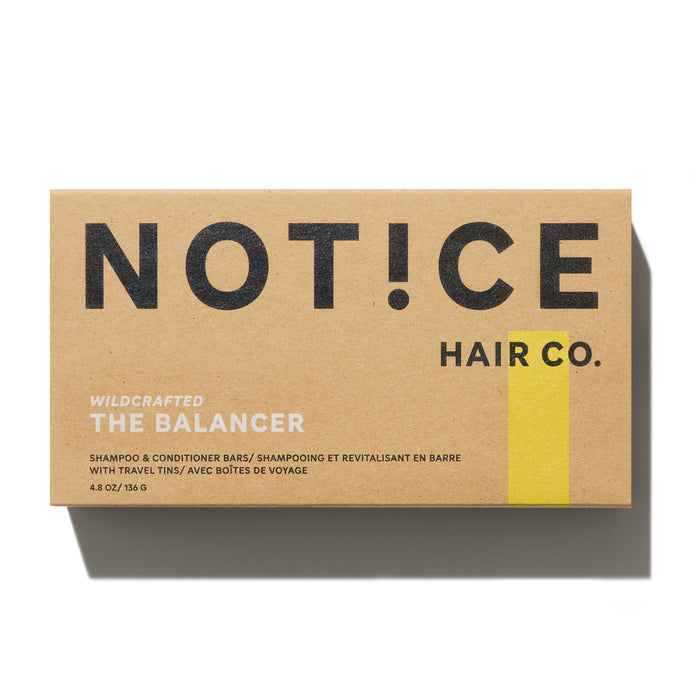 The brown cardboard packaging reads NOT!CE Hair Co in bold black, with Wildcrafted The Balancer in white below. It encases plastic-free shampoo and conditioner bars ideal for frizzy hair. A yellow vertical stripe adorns the right side of the box.