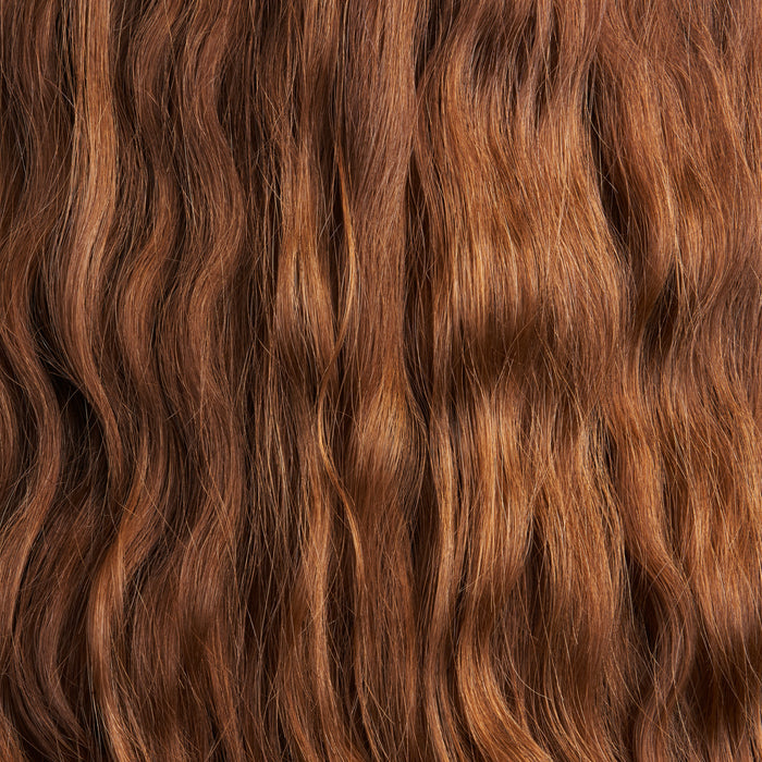 Close-up of long, wavy auburn hair with a natural sheen, rich in red and brown tones. NOT!CE Hair Cos The Balancer Travel Set, featuring plastic-free shampoo & conditioner bars, enhances the soft volume and gentle cascading waves.