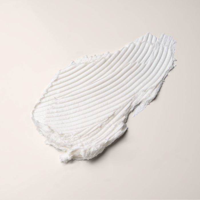 A smooth, thick smear of white Everist The Body Wash Concentrate Travel Mini is spread across a flat, light-colored surface, with visible ridged lines left by a spreading tool.