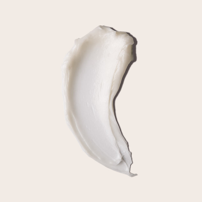 A rich, creamy white smear of Everist’s The Deep Conditioning Concentrate Tin is displayed on light beige, showcasing its thick texture—ideal for hydrating all hair and skin types.