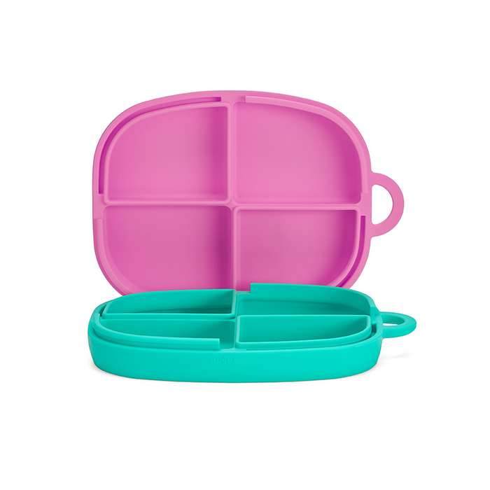 The Everything Plate by morepeas is a colorful, eco-friendly bento box made of food-grade silicone. It features a teal bottom with four compartments and a bright pink lid. Secure handles ensure its both functional and fun for every meal.