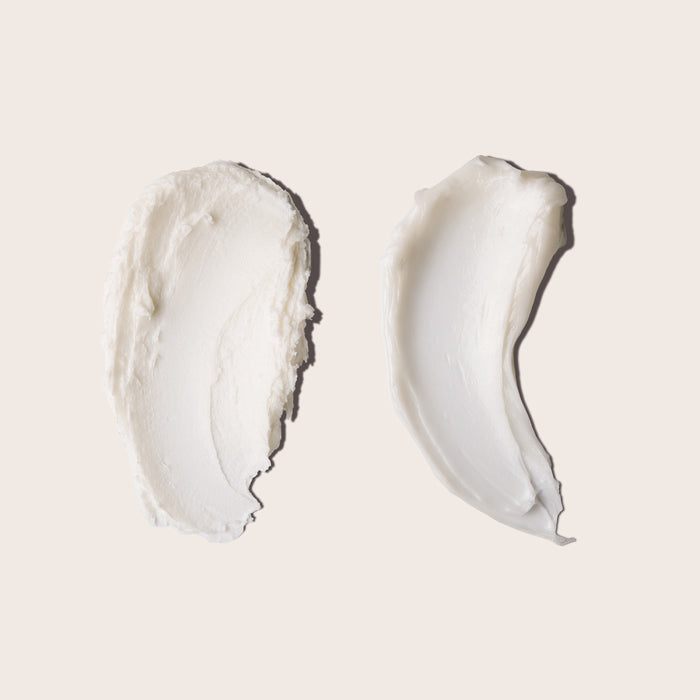 Two creamy, white swatches of Everist’s The Haircare Meets Skincare Set are spread in ovals on a beige background, their thick, glossy textures evoking the nourishing luxury of haircare infused with skincare benefits.