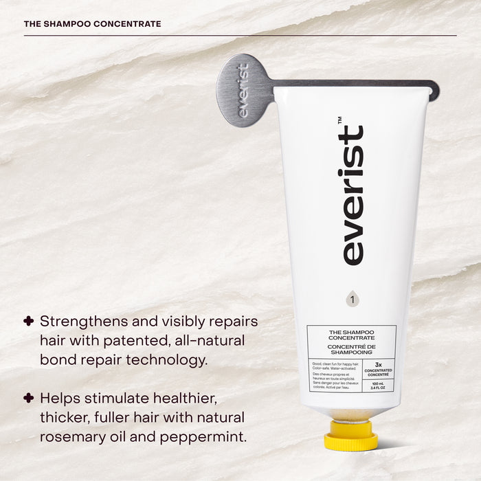A white tube from Everist's The Haircare Meets Skincare Set, paired with a gray key, is displayed on a textured background. Text highlights its clean haircare formula and bond repair tech for healthy, thicker hair with rosemary oil and peppermint.