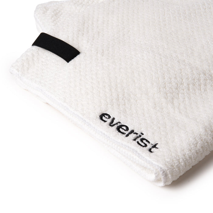 A close-up of Everist’s The Quick-Dry Hair Towel, a folded white textured microfibre towel featuring a black fabric loop and everist embroidered on the corner, designed to reduce frizz and speed up drying.