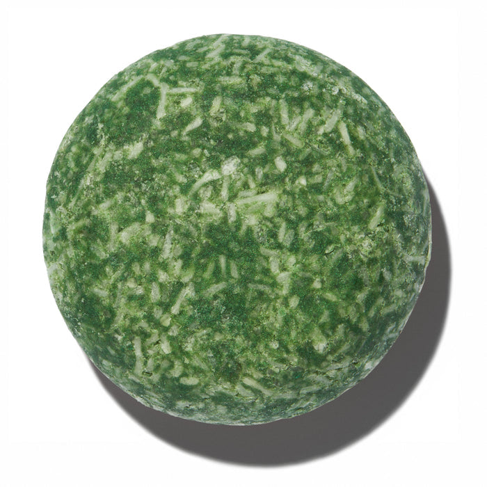 A round, green bar from NOT!CE Hair Co, The Stimulator Shampoo Bar has a textured surface with white specks. Isolated on a white background, this plastic-free essential not only cleanses but also promotes hair growth for luscious locks.