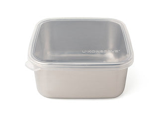 The U-Konserve To-Go Large Container is a square, stainless steel eco-friendly container with a simple design and smooth finish, featuring an easy-open clear plastic lid with a slight lip.