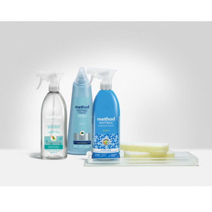Three method Toilet Cleaner bottles with blue and clear liquid and antibacterial labels, plus two sponges, arranged on a clear tray against a light gray background. These cleaners help kill germs.