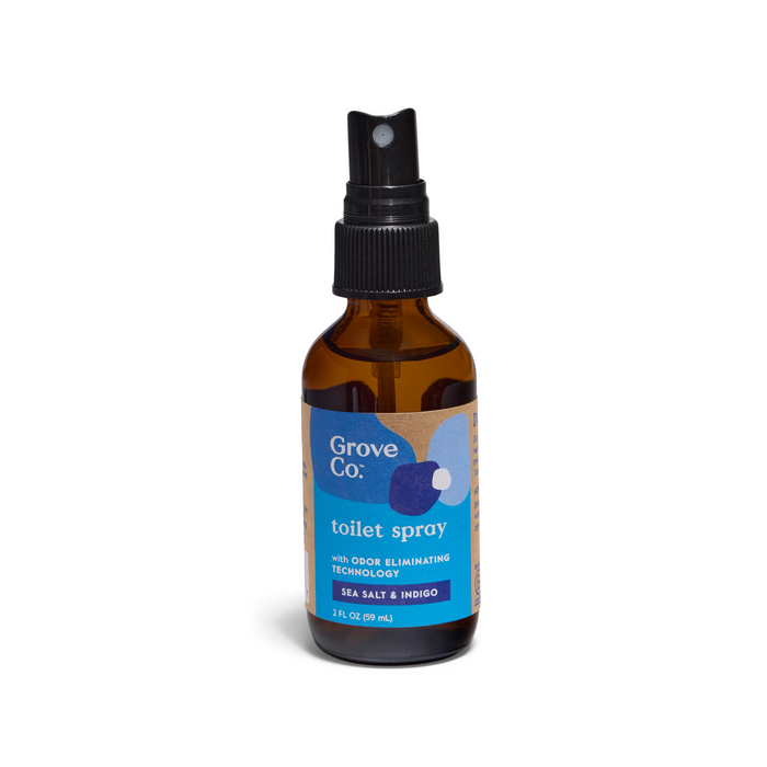 A 2 fl oz (59 mL) Grove Co. Toilet Spray in Sea Salt & Indigo fragrance, housed in a brown glass bottle with a black spray nozzle, offering advanced odor-elimination technology.