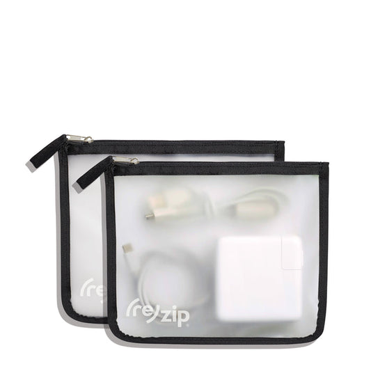 Two translucent, reusable Travel Organizer Zipper Bags - Medium by (re)zip, with black borders, hold electronic accessories like a power adapter and cables. These travel bags are displayed on a white background.