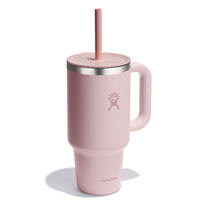 The Hydro Flask Travel Tumbler, 32 oz, is pink with a handle, straw-friendly leak-resistant lid, and sports double-wall vacuum insulation. It features a stainless steel rim and the Hydro Flask logo.