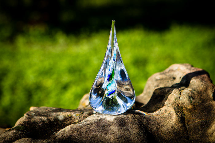Tri-color glass memorial pyramid flame with cremation ash visible as a spiral inside a clear teardrop-shaped piece
