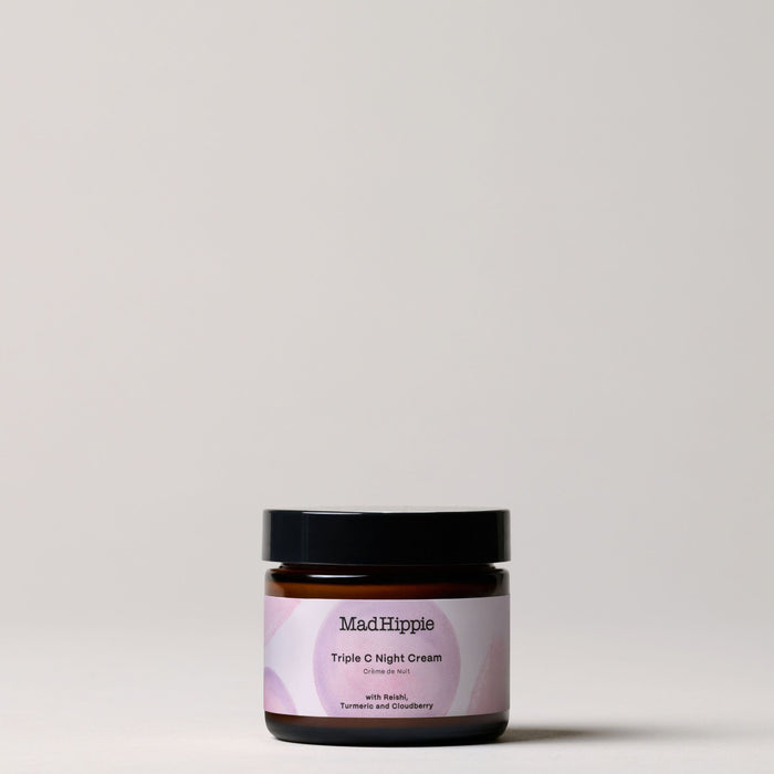 Mad Hippies Triple C Night Cream, a standout in natural skin care, is showcased against a light gray background. Its dark jar contrasts with a white and pink label highlighting potent ingredients like Reishi, Turmeric, Gooseberry, and nourishing vitamin C.
