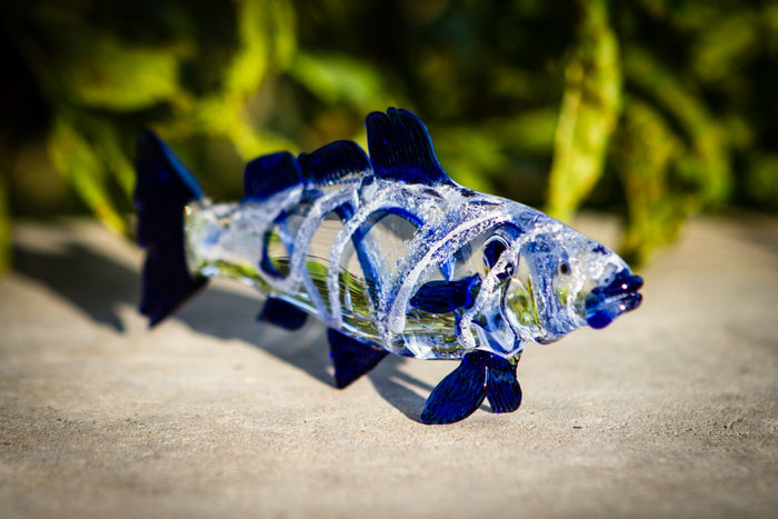 Blue accented glass trout figurine shown from the side with cremains embedded.