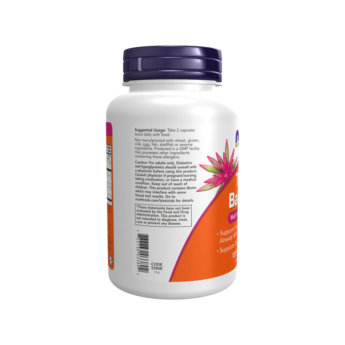 A white bottle of True Balance Multi Vitamin & Mineral by NOW Foods features a purple cap and an abstract flower design. The label includes instructions and ingredients supporting healthy carbohydrate metabolism. The bottle is angled to show the front and one side.