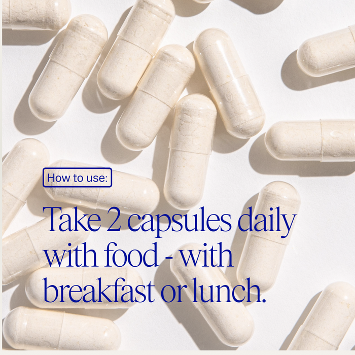 Several white capsules from Ora Organic’s Trust Your Gut: Daily Pre + Probiotic Capsule are scattered on a light surface. Text overlay reads: “How to use: Take 2 capsules daily with food, ideally at breakfast or lunch, to support gut health.”.