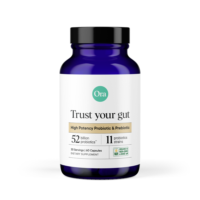A blue bottle labeled Ora Organic Trust Your Gut: High Potency Pre + Probiotic Capsules contains 60 vegan, organic, non-GMO capsules with 52 billion probiotics from 11 strains to support microbiome recovery.
